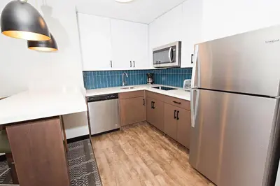 a kitchen with a stainless steel refrigerator and wooden floors at Staybridge Suites - Denver North - Thornton by IHG in Thornton