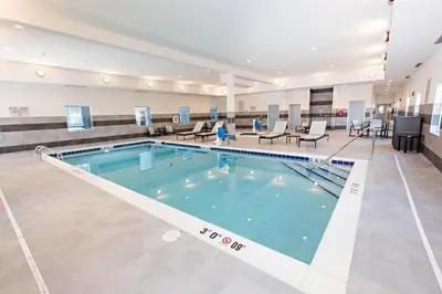 a large swimming pool in a building with chairs and tables at Staybridge Suites - Denver North - Thornton by IHG in Thornton