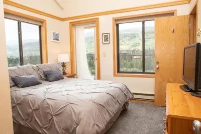 a bedroom with a bed and a tv and windows at 2800 Slopeside condo in Keystone