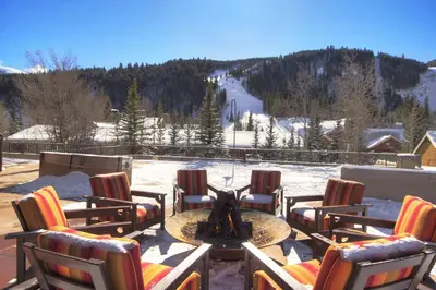 a patio with chairs and a fire pit in the snow at 2800 Slopeside condo in Keystone