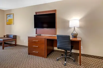 a hotel room with a desk with a television and a chair at Comfort Suites Broomfield-Boulder-Interlocken in Broomfield