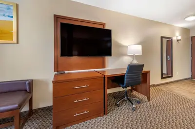 a hotel room with a desk with a television and a chair at Comfort Suites Broomfield-Boulder-Interlocken in Broomfield