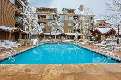 a pool in front of a hotel with snow covered trees at Black Bear 2 Bed 2 Bath BBCS in Dillon