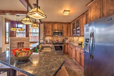 a kitchen with wooden cabinets and a stainless steel refrigerator at Fraser Condo with Views and Hot Tub Near Winter Park! in Fraser