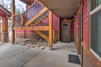 a wooden staircase on a pink house with rocks at Fraser Condo with Views and Hot Tub Near Winter Park! in Fraser