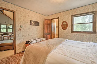 a bedroom with a large bed and a mirror at 2 Mi to Grand Lake Cabin with Fireplace and Library! in Grand Lake