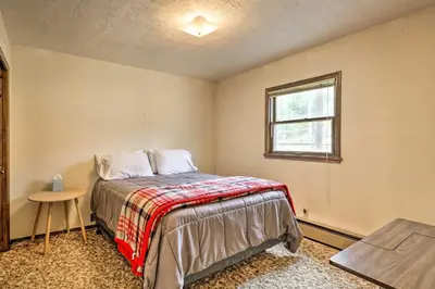 a bedroom with a bed with a table and a window at 2 Mi to Grand Lake Cabin with Fireplace and Library! in Grand Lake