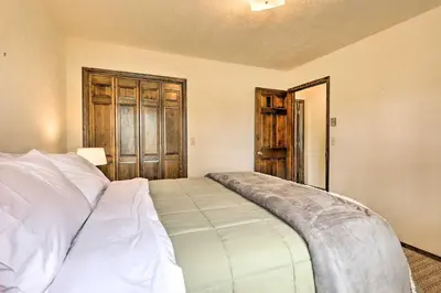 a bedroom with a bed and a wooden door at 2 Mi to Grand Lake Cabin with Fireplace and Library! in Grand Lake