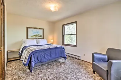 a bedroom with a bed and a chair at 2 Mi to Grand Lake Cabin with Fireplace and Library! in Grand Lake