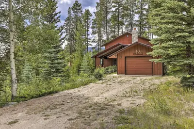 a house with a garage in the woods at 2 Mi to Grand Lake Cabin with Fireplace and Library! in Grand Lake