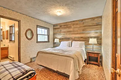 a bedroom with a bed and a wooden wall at 2 Mi to Grand Lake Cabin with Fireplace and Library! in Grand Lake