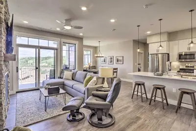 a living room with a couch and a kitchen at Winter Park Condo with Fireplace - 4 Mi to Slopes! in Winter Park