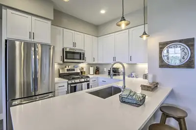 a kitchen with white cabinets and a stainless steel refrigerator at Winter Park Condo with Fireplace - 4 Mi to Slopes! in Winter Park