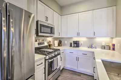 a kitchen with white cabinets and a stainless steel refrigerator at Winter Park Condo with Fireplace - 4 Mi to Slopes! in Winter Park
