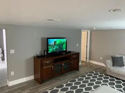 a living room with a flat screen tv on a cabinet at DIA HideAway -2BR, 15 min from DIA DT, Anschutz MD in Commerce City