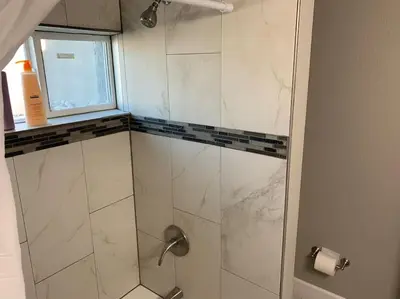 a shower with a glass door and a window at DIA HideAway -2BR, 15 min from DIA DT, Anschutz MD in Commerce City
