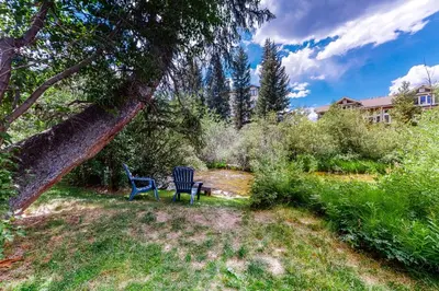 two blue chairs sitting in a yard under a tree at Hi Country Haus 11-2 in Winter Park