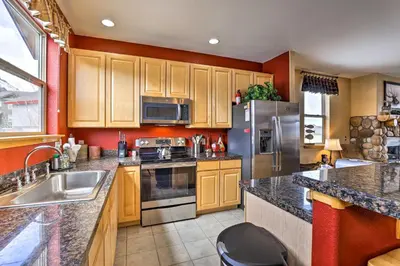 a kitchen with wooden cabinets and a stainless steel refrigerator at 11 Mi to Keystone Silverthorne Condo with Deck in Silverthorne