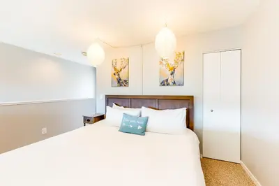 a bedroom with a large white bed and two chandeliers at Watch Hill Lofted in Silverthorne