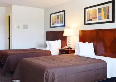 a hotel room with two beds and a lamp at GREELEY UNIVERSITY INN/ GREELEY INN in Greeley