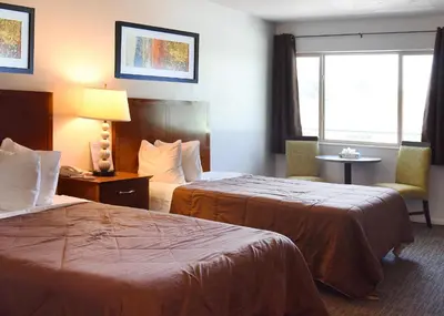 a hotel room with two beds and a window at GREELEY UNIVERSITY INN/ GREELEY INN in Greeley