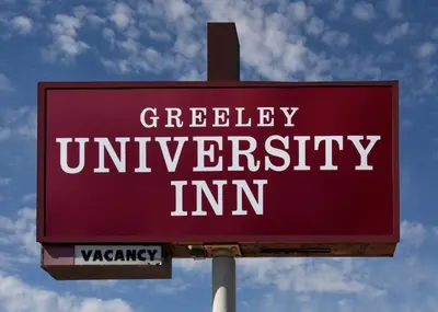 a sign that says greedy university inn on a pole at GREELEY UNIVERSITY INN/ GREELEY INN in Greeley