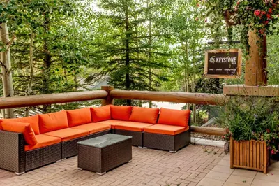 an orange couch sitting on a patio with trees at Arapahoe Lodge by Summit County Mountain Retreats in Keystone