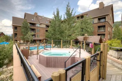 a deck with a hot tub and a building at Arapahoe Lodge by Summit County Mountain Retreats in Keystone