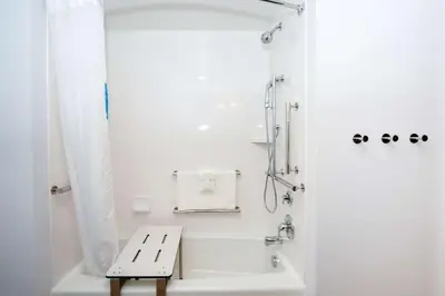 a white bathroom with a shower and a bench at Hampton Inn & Suites Aurora South, Co in Aurora
