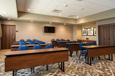 a conference room with blue chairs and tables and a tv at Hampton Inn & Suites Aurora South, Co in Aurora