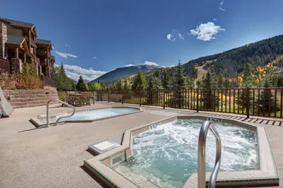 a hot tub on a patio with mountains in the background at Hidden River Lodge by Summit County Mountain Retreats in Keystone