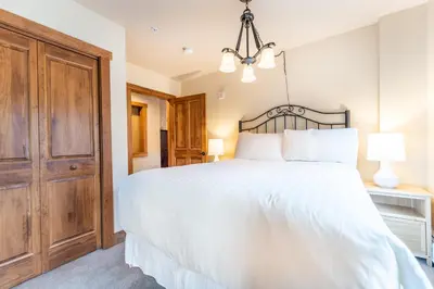 a bedroom with a large white bed and a chandelier at Red Hawk Lodge by Summit County Mountain Retreats in Keystone