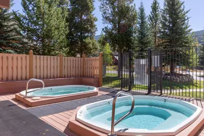 a jacuzzi tub in a backyard with a fence at Snake River Village by Summit County Mountain Retreats in Keystone