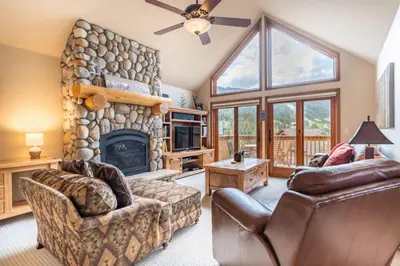 a living room with a stone fireplace and leather furniture at Snake River Village by Summit County Mountain Retreats in Keystone