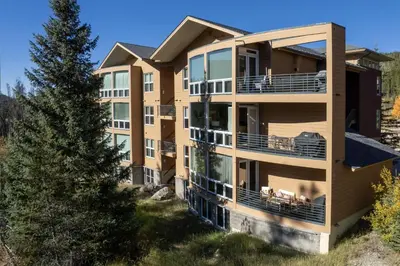 an apartment building with balconies and a tree at Trademark Condo Short Walk to Shuttle in Winter Park