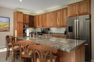 a kitchen with wooden cabinets and a stainless steel refrigerator at Trademark Condo Short Walk to Shuttle in Winter Park