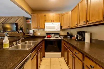 a kitchen with wooden cabinets and a sink and a microwave at Flying Dutchman by Summit County Mountain Retreats in Keystone