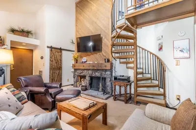 a living room with a staircase and a fireplace at Flying Dutchman by Summit County Mountain Retreats in Keystone