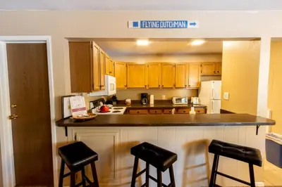 a kitchen with wooden cabinets and black bar stools at Flying Dutchman by Summit County Mountain Retreats in Keystone