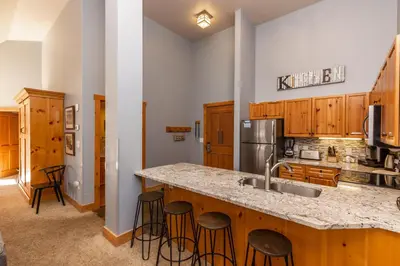 a kitchen with wooden cabinets and a counter with bar stools at Expedition Station by Summit County Mountain Retreats in Keystone