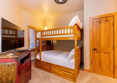 a bedroom with two bunk beds and a flat screen tv at Expedition Station by Summit County Mountain Retreats in Keystone