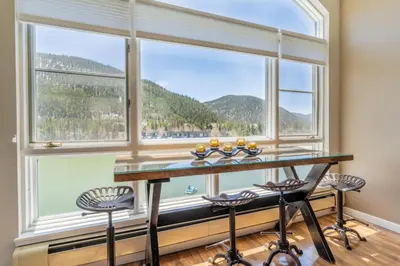 a room with a large window with a table and stools at Lakeshore by Summit County Mountain Retreats in Keystone