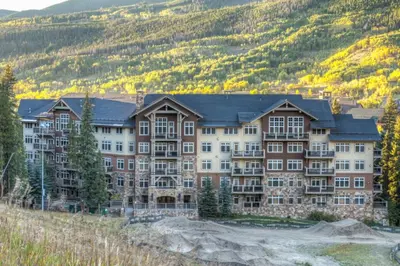 a large building on a hill with mountains in the background at Lone Eagle by Summit County Mountain Retreats in Keystone