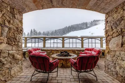 a patio with red chairs and a table with a view at Lone Eagle by Summit County Mountain Retreats in Keystone
