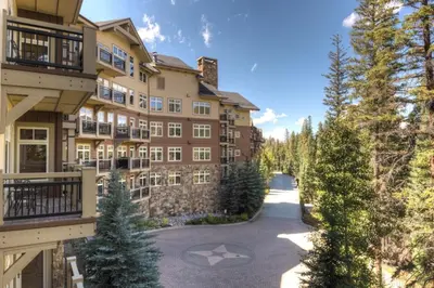 an apartment building with a driveway and trees at Lone Eagle by Summit County Mountain Retreats in Keystone