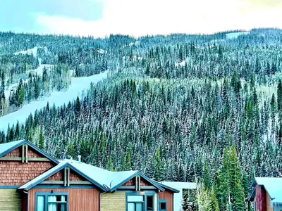 a house with snow on it in front of a mountain at River Run Townhomes by Summit County Mountain Retreats in Keystone