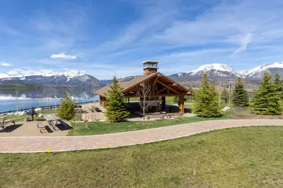 a gazebo with a lake and snow covered mountains at The Lodge at Lake Dillon 111 in Dillon