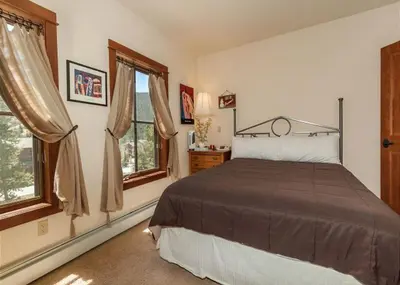 a bedroom with a bed and two windows at Oro Grande by Summit County Mountain Retreats in Keystone