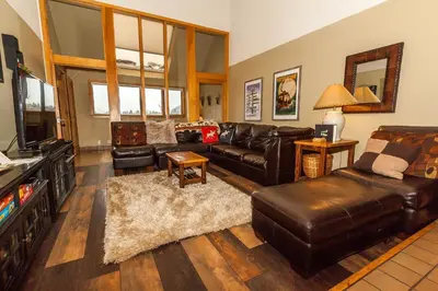 a living room with a leather couch and a television at Pines by Summit County Mountain Retreats in Keystone