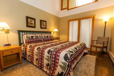 a bedroom with a large bed and a chair at Pines by Summit County Mountain Retreats in Keystone